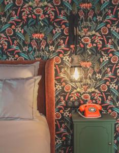 a bedroom with a bed and a red phone on a night stand at La Maison Hôtel Mulhouse Centre in Mulhouse