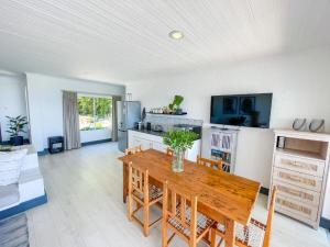 a living room with a wooden table and a kitchen at The White House in Knysna