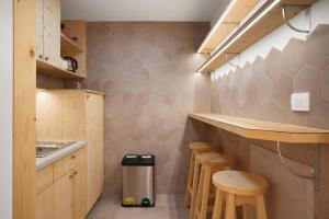 a small kitchen with a counter and stools in it at Honeybee Hostel - Hiša kranjske čebele in Višnja Gora