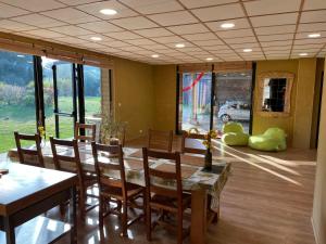 uma sala de jantar com mesa, cadeiras e janelas em Holiday home on farm (La Ferme du Tao) em Beaugies-sous-Bois