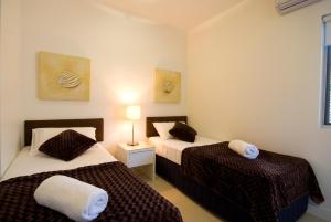 a hotel room with two beds and two lamps at Beachside Magnetic Harbour Apartments in Nelly Bay