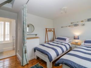 two beds in a bedroom with white walls and wood floors at 46 Crowthers Hill in Dartmouth
