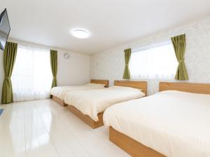 een slaapkamer met 2 bedden en ramen met gordijnen bij Kinugawa Station Front room A in Nikko