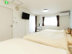 a bedroom with two beds and a tv on the wall at Kinugawa Station Front room B in Nikko