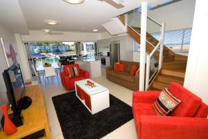 a living room with red furniture and a staircase at Beachside Magnetic Harbour Apartments in Nelly Bay