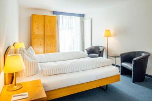 Habitación de hotel con 2 camas, mesa y sillas en Hotel-Restaurant Bellevue, en Flims