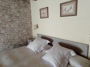 a bedroom with a bed with two pillows and a stone wall at Can Bayre-Casa Rural in Fortiá