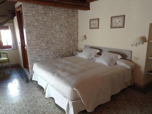 1 dormitorio con 1 cama grande y pared de piedra en Can Bayre-Casa Rural, en Fortià