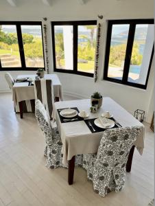 ein Esszimmer mit Tischen, Stühlen und Fenstern in der Unterkunft Cambalala Guest House in Knysna