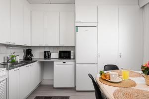 a kitchen with white cabinets and a table with a bowl of fruit at Apartments Borg Wellamo in Pori