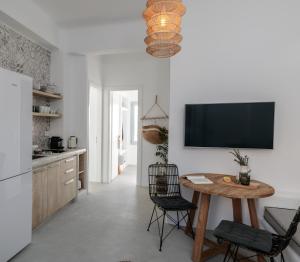 a kitchen with a table and a tv on the wall at Anamnesia boutique apartments Naxos town in Naxos Chora