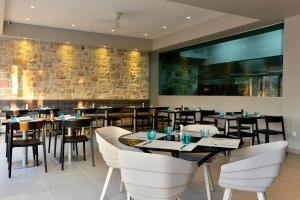 a restaurant with tables and chairs and a stone wall at Hotel Osam - Adults Only in Supetar