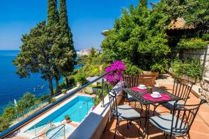 uma varanda com uma mesa e cadeiras ao lado de uma piscina em Luxury Beachfront Villa Dubrovnik Palace with private pool and jacuzzi by the beach in Dubrovnik em Dubrovnik