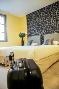 a hotel room with two beds and a suitcase at Hotel Le Petit Perier in Laval