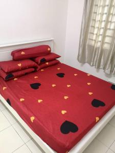uma cama com um edredão vermelho com borboletas em Adieza Homestay Dmuslim em Malaca