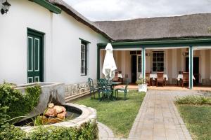 
a house with a lawn chair and patio furniture at De Doornkraal Vinotel in Riversdale
