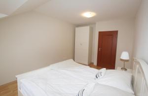 1 dormitorio con cama blanca y puerta marrón en Apartmán U krále - 3, en Jičín