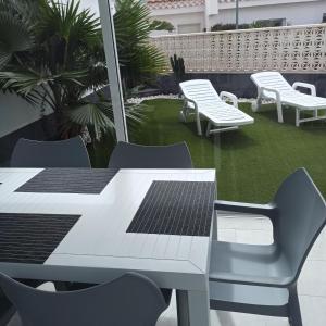 un tavolo bianco e sedie su un patio con prato di Bruna's house ad Adeje
