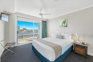 Habitación de hotel con cama y balcón en Port Pacific Resort en Port Macquarie