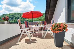 uma mesa e cadeiras numa varanda com um guarda-sol vermelho em Ferienwohnungen Fanderl em Riedenburg