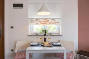 a white dining room with a white table and chairs at Apartmani Škopac Rabac in Rabac