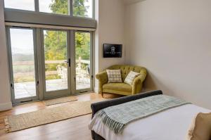a bedroom with a bed and a chair and sliding glass doors at Cheltenham View Lodge in Cheltenham
