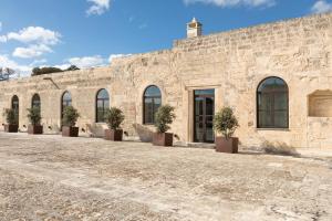 un bâtiment en pierre avec des plantes en pot devant lui dans l'établissement Chiostro dei Domenicani - Dimora Storica, à Lecce