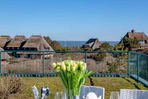 een vaas met bloemen op een tafel voor een hek bij Haus Meerblick in List