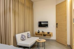 a room with a white chair and a television at Iris Suites in Bangalore