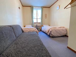 a living room with two beds and a couch at Pension Green Grass in Chino