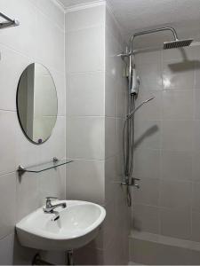 ein Bad mit einem Waschbecken, einem Spiegel und einer Dusche in der Unterkunft Qs and YPJs 2BR Condo One Oasis Cagayan de Oro in Cagayan de Oro