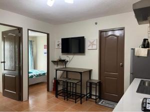 a room with a kitchen with a table and a television at Qs and YPJs 2BR Condo One Oasis Cagayan de Oro in Cagayan de Oro