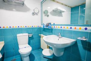 Baño de azulejos azules con aseo y lavamanos en Motel Venus Santiago en Luou