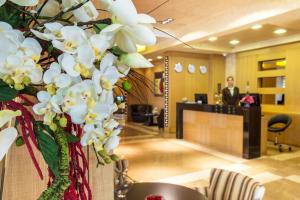 Eine Lobby mit weißen Orchideen und einem Mann im Hintergrund in der Unterkunft Landmark Creek Hotel & Wellness in Plowdiw
