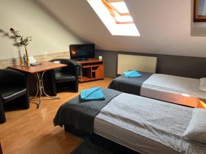 Pokój z 2 łóżkami, stołem i telewizorem w obiekcie Zajazd Grodzki w Koninie