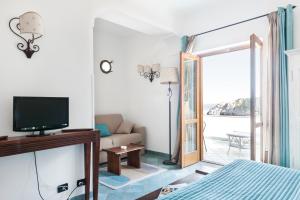 a room with a bed and a television and a living room at La Conca del Sogno in Massa Lubrense