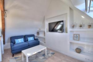uma sala de estar com um sofá azul e uma televisão em Rêves Bleus - Côte de Granit Rose em Ploubezre