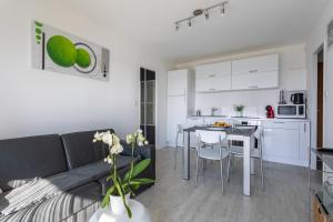 a living room and kitchen with a couch and a table at Le P'tit Idéal in Cabourg
