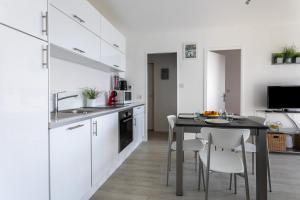 a kitchen with white cabinets and a table with chairs at Le P'tit Idéal in Cabourg