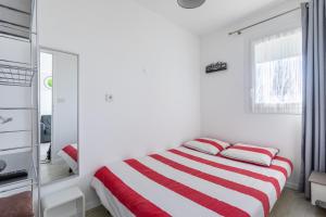 a white bedroom with a red and white striped bed at Le P'tit Idéal in Cabourg +4 photos
