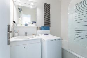 a white bathroom with a sink and a mirror at Le P'tit Idéal in Cabourg