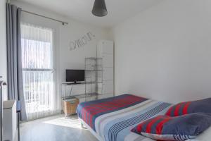 a white bedroom with a bed and a television at Le P'tit Idéal in Cabourg