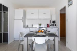 a kitchen with a table with white cabinets and white chairs at Le P'tit Idéal in Cabourg