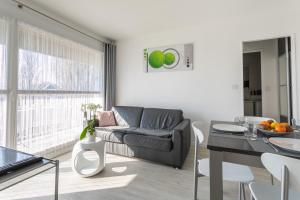 a living room with a couch and a table at Le P'tit Idéal in Cabourg