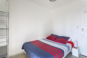 a bedroom with a bed with red and blue pillows at Le P'tit Idéal in Cabourg