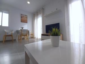 a white living room with a table and a tv at Casa Ortiz with private roof terrace - oceanview in Conil de la Frontera