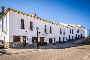 a large white building on the side of a street at Apartamentos La Venta del Charco in Cardeña