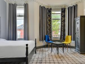 a room with a bed, chair, table and window at Empire Hotel in Leicester