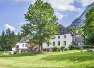 una grande casa bianca con un albero in cortile di JUFA Hotel Grundlsee a Grundlsee