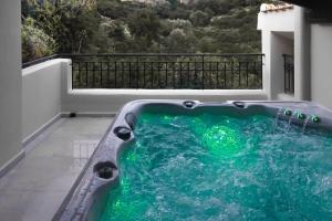 una vasca idromassaggio su un balcone con acqua verde di Villa Ventus, 40sqm private pool & hot tub! a Roussospítion